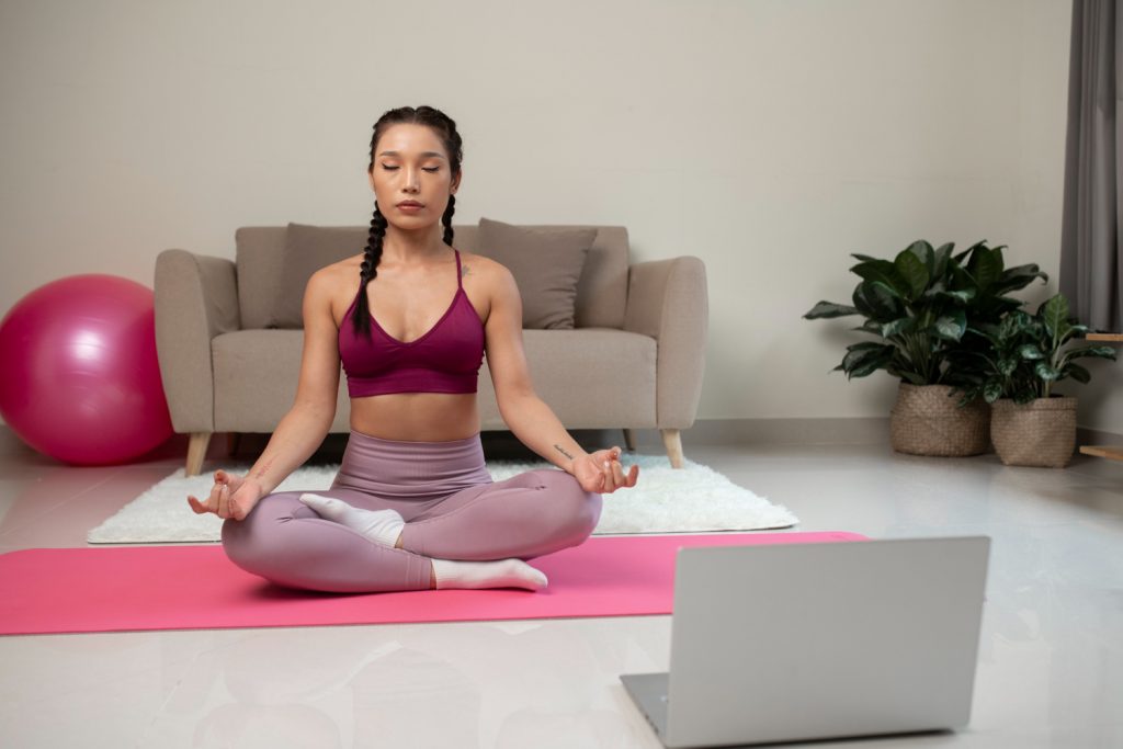 Femme faisant du yoga après un instructeur de fitness en ligne