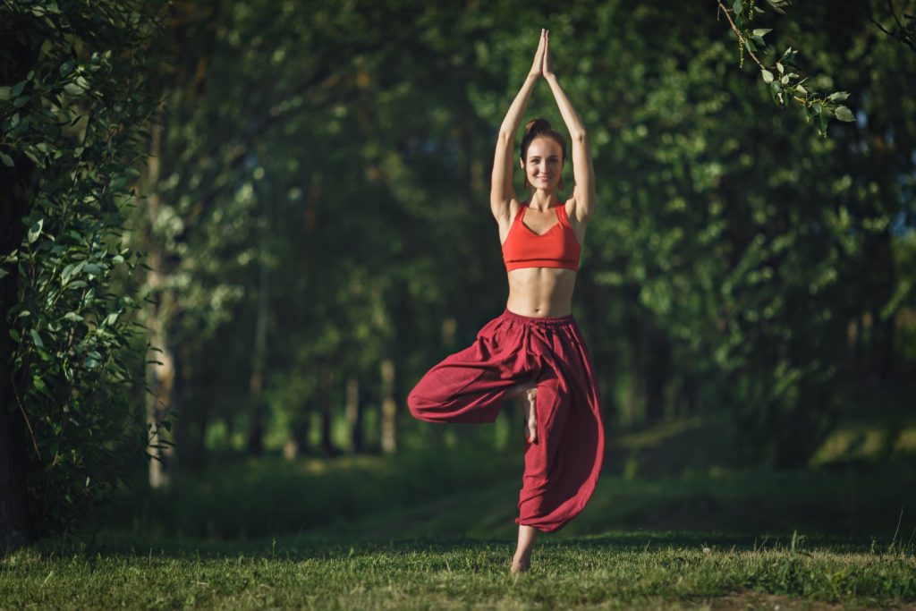 Jeune femme faisant des exercices de yoga dans le parc de la ville d'été